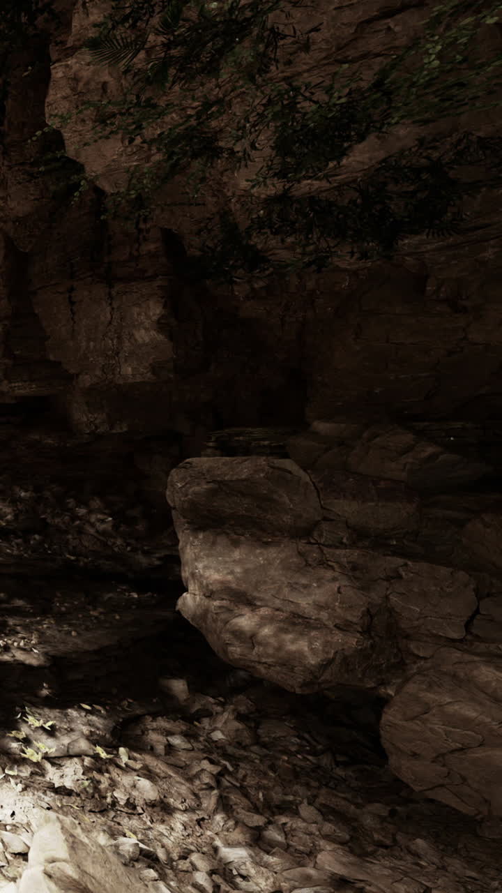 Formazioni rocciose in una grotta con ombre e pietre sparse vicino a un corso d'acqua