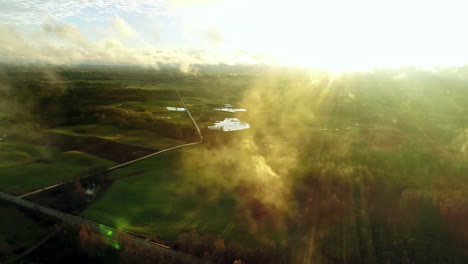 drone flying through clouds with green countryside in background