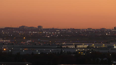 Airplane-lands-Toronto-airport-under-red-orange-sunset-haze-sky-at-dusk