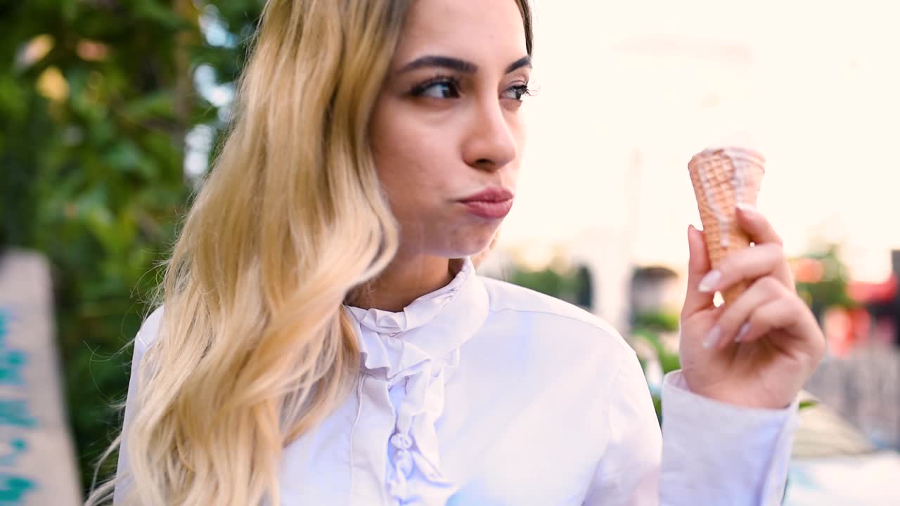 슬로우 모션:유럽의 거리에 앉아 있는 동안 아름다운 소녀가 아이스크림을 먹는다