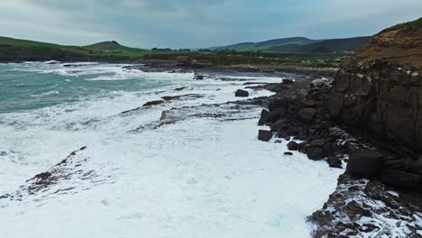 Aerial-pullback-above-water-churning-across-rocky-sharp-jagged-surface-as-it-drains-into-ocean