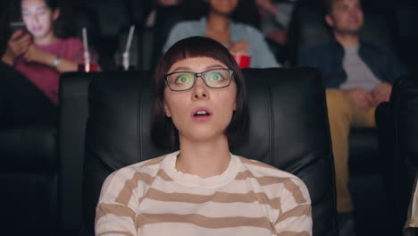 woman in movie theater reacts to a surprising movie scene