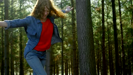 mujer caminando sobre un tronco de madera en el bosque 4k