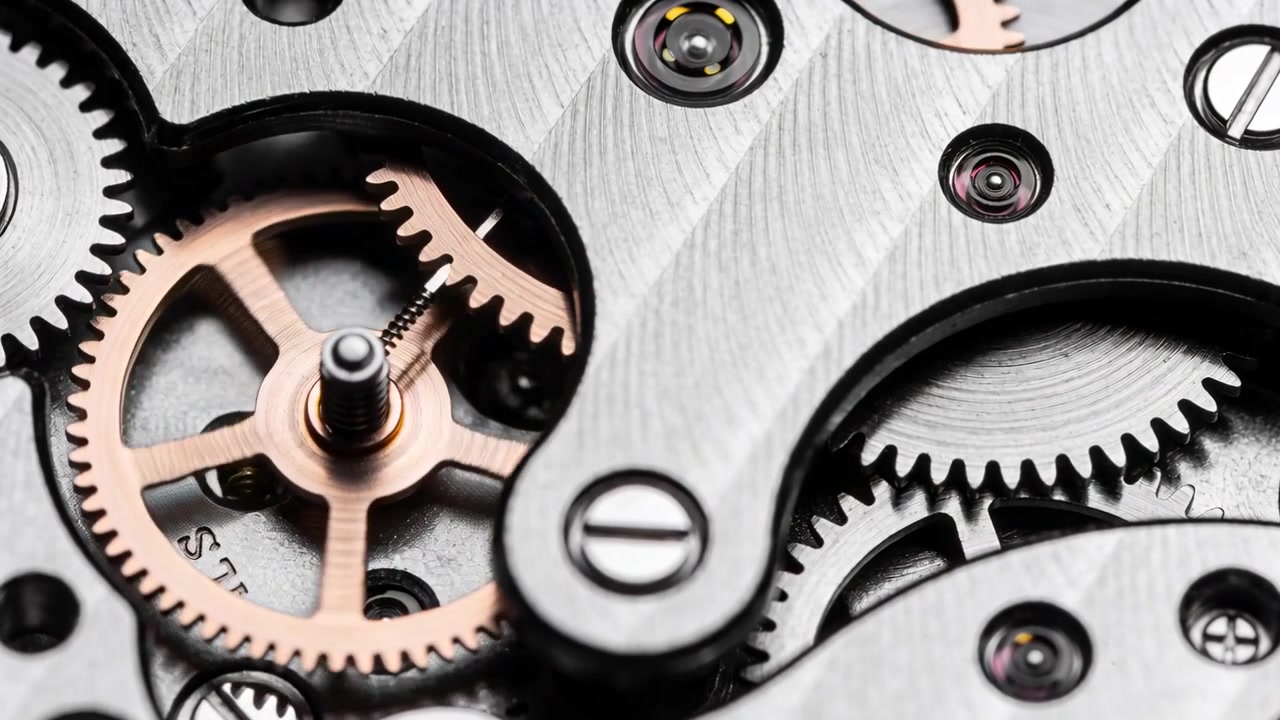 Driving watch gears via spring tension, advancing in closeup, rose gold gear engaging steel wheel