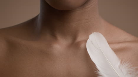 close-up of woman's chest and neck with a feather