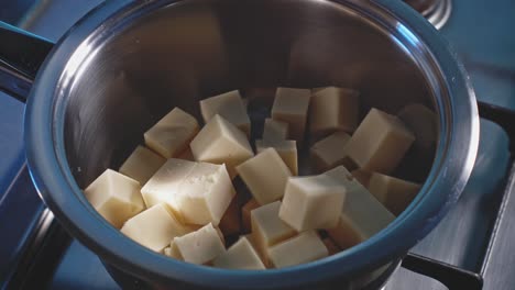 Poner-Queso-En-Cubos-Y-Leche-En-Una-Olla-De-Acero-Inoxidable