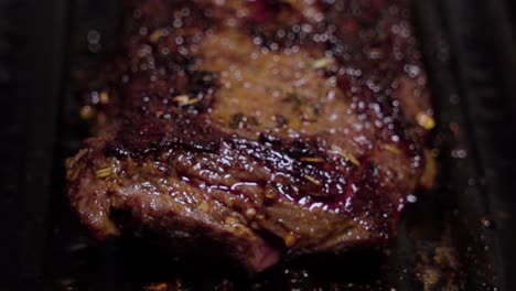 tilt up, delicious steak cooks on cast iron grill, closeup selective focus