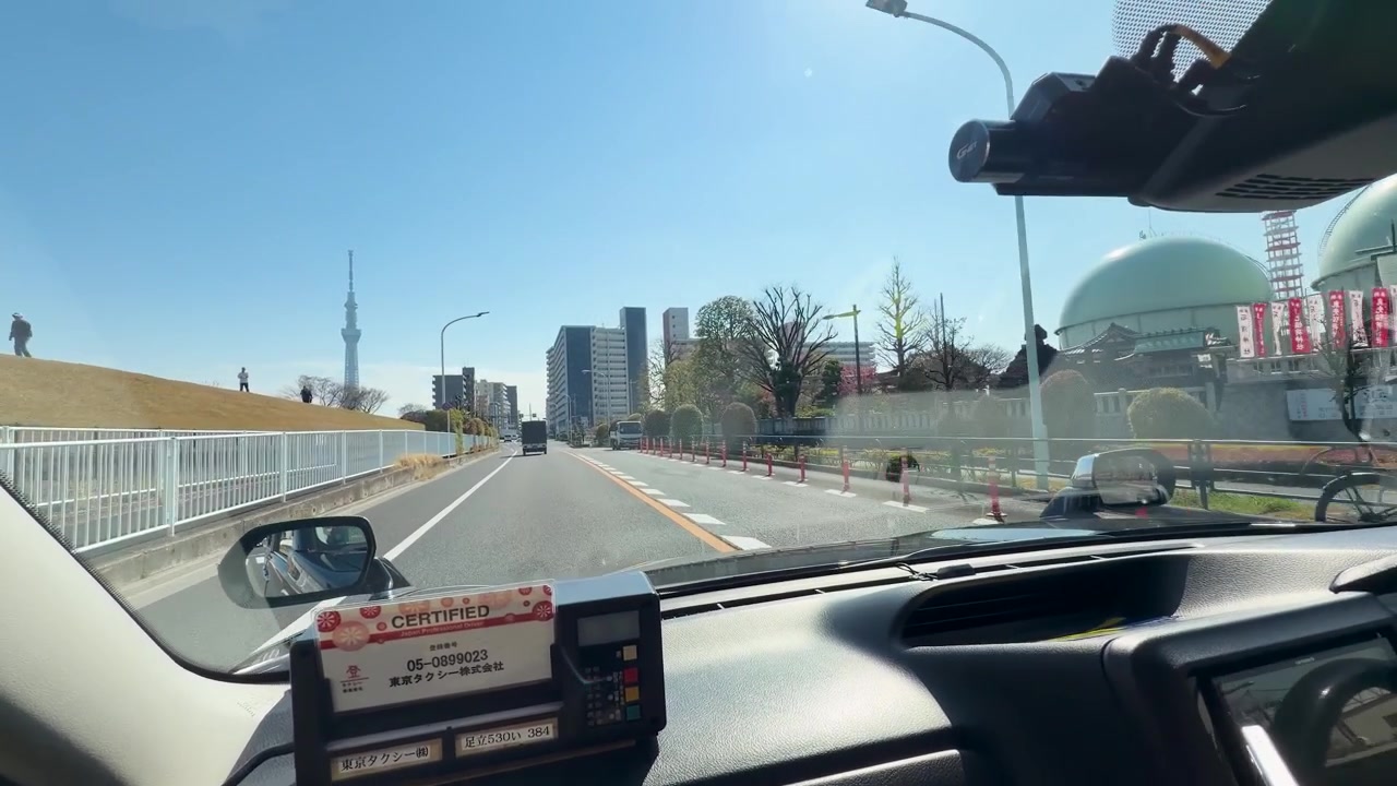 第一人称仪表盘视角捕捉到一辆汽车在东京阳光明媚的城市道路上行驶。