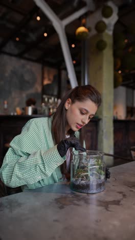 mujer cuidando plantas en un café moderno