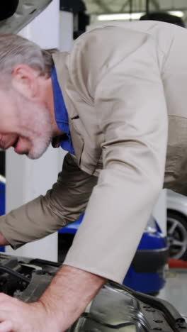 mechanic checking car engine oil and showing thumbs up