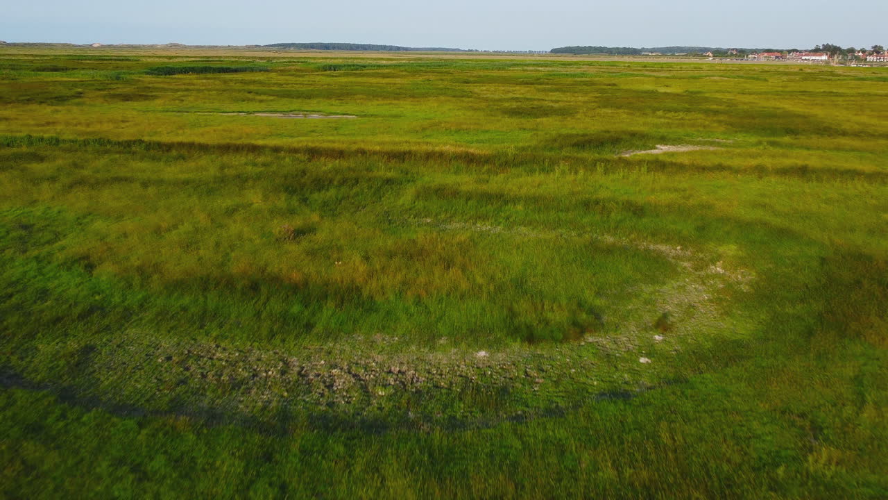 disparo aéreo de drones volando sobre marismas verdes con burnham overy staithe en el fondo en el norte de norfolk, reino unido