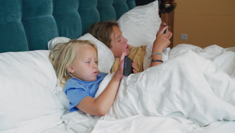 children using gadgets in bed