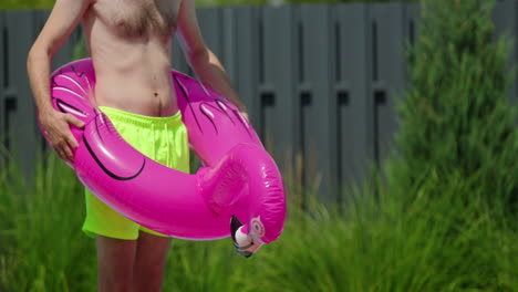 hombre sosteniendo un flotador de piscina de flamenco rosa