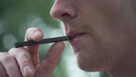 close up of male model smoking vaporizer outside 60fps