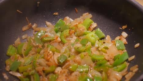 close up of huge wok while frying onions and green bell peppers in oil and deep pan