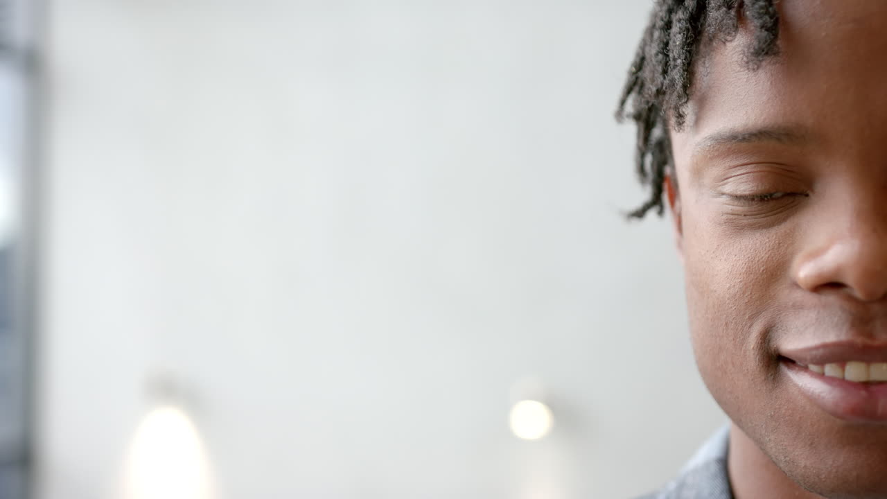 Smiling young man with closed eyes, enjoying peaceful moment indoors, copy space