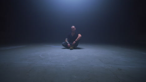 man sitting in dark studio