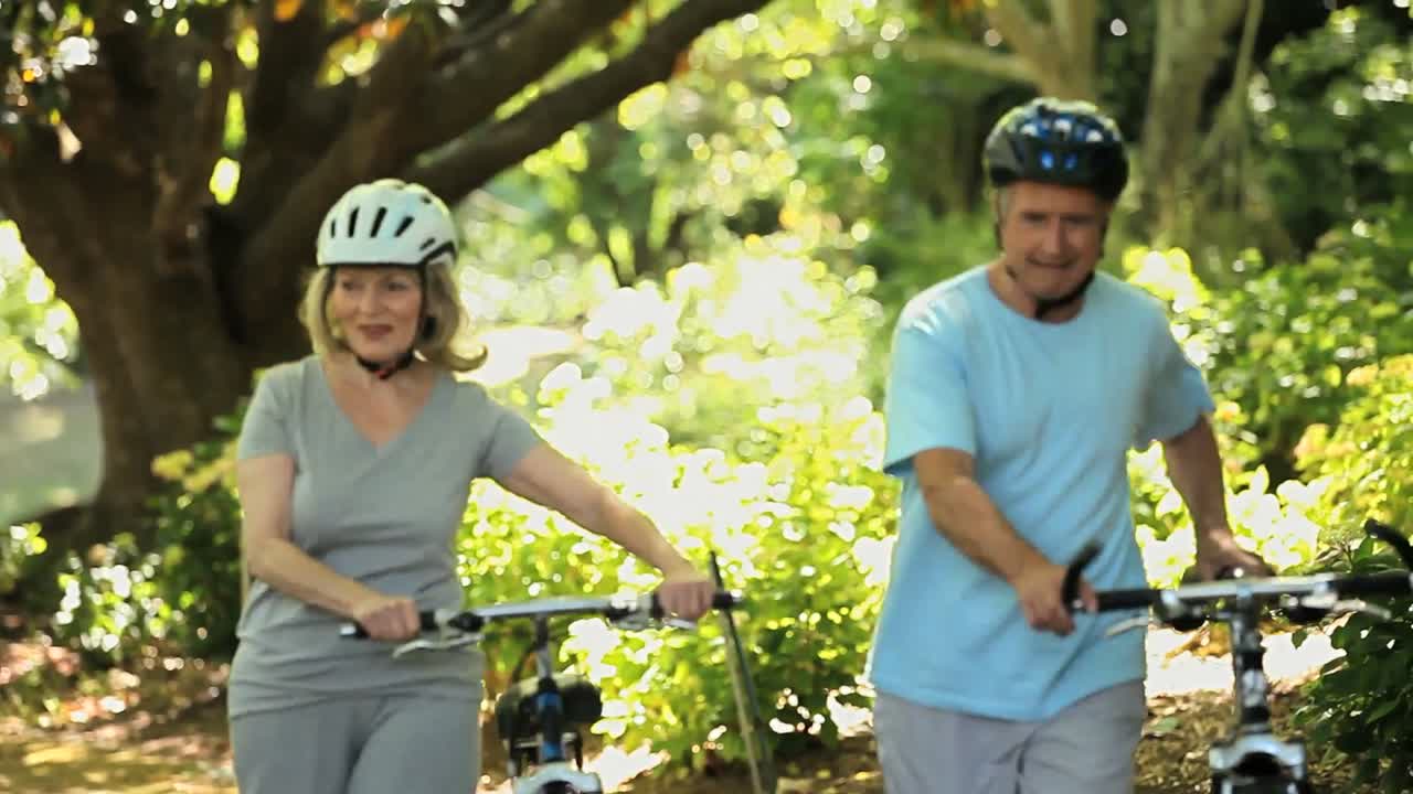 pareja de ancianos caminando y empujando bicicletas