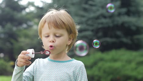 portrait of funny lovely little girl blowing soap bubbles finally looks into the camera slow motion portrait of funny lovely little girl blowing soap bubbles slow motion close up