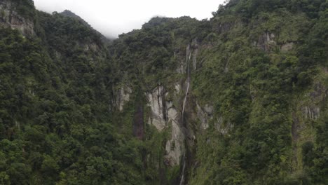 Aerial-push-in-towards-Taiwan-rocky-lush-jungle-mountain-wilderness-rising-to-peaks-above