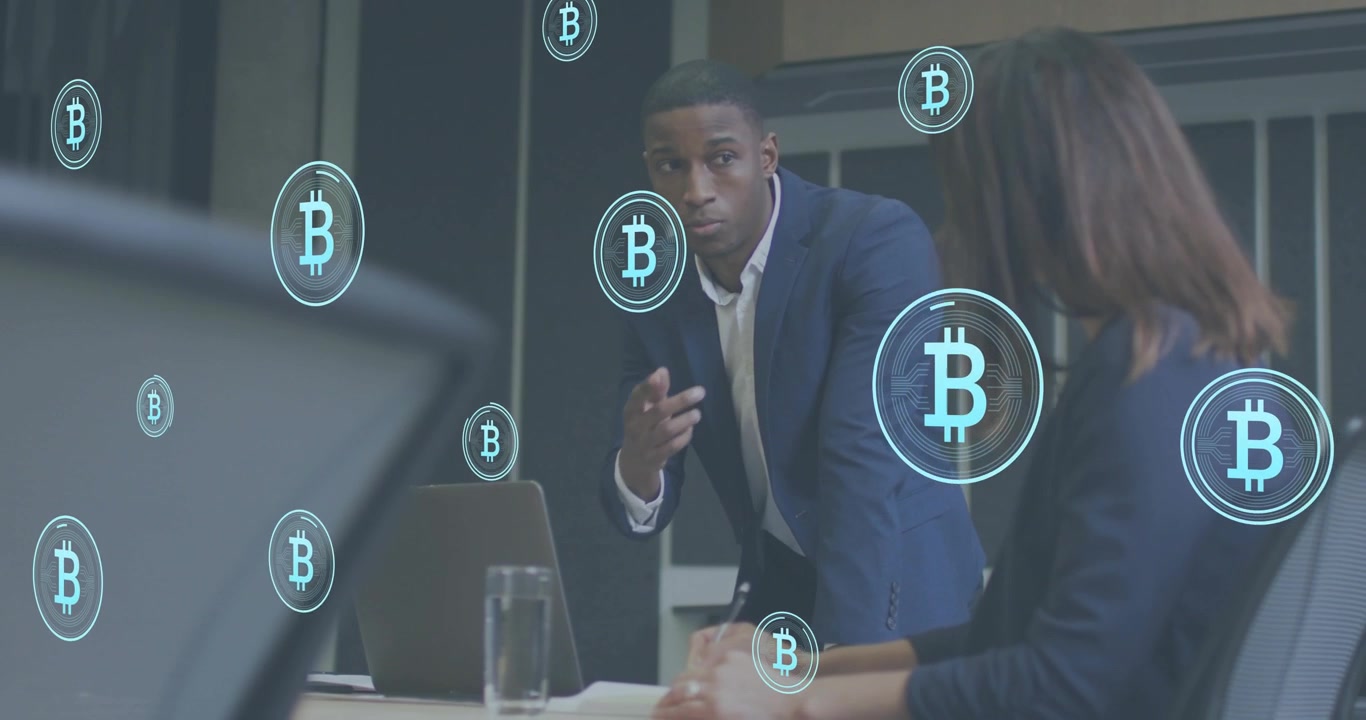 Dirigente che discute di finanza e genera icone animate di Bitcoin intorno al laptop con un collega che prende appunti.