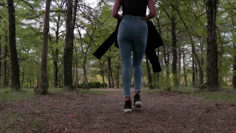 Girl-with-long-legs-walking-on-a-forest-path-low-angle-shot