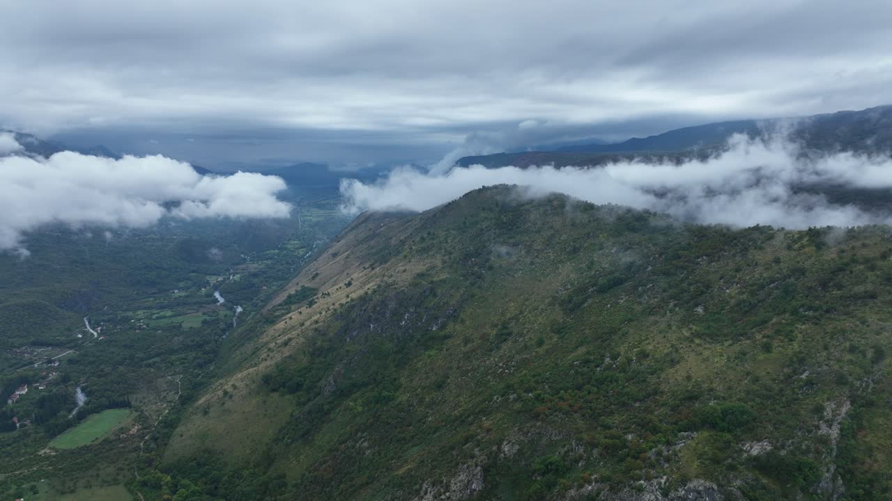 Green mountain ridge with drifting clouds and valley streams near Cetinje, Montenegro. Aerial view
