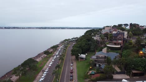 Aerial-view-of-cars-driving-down-the-coastline-in-beautiful-Posadas,-Misiones,-Argentina