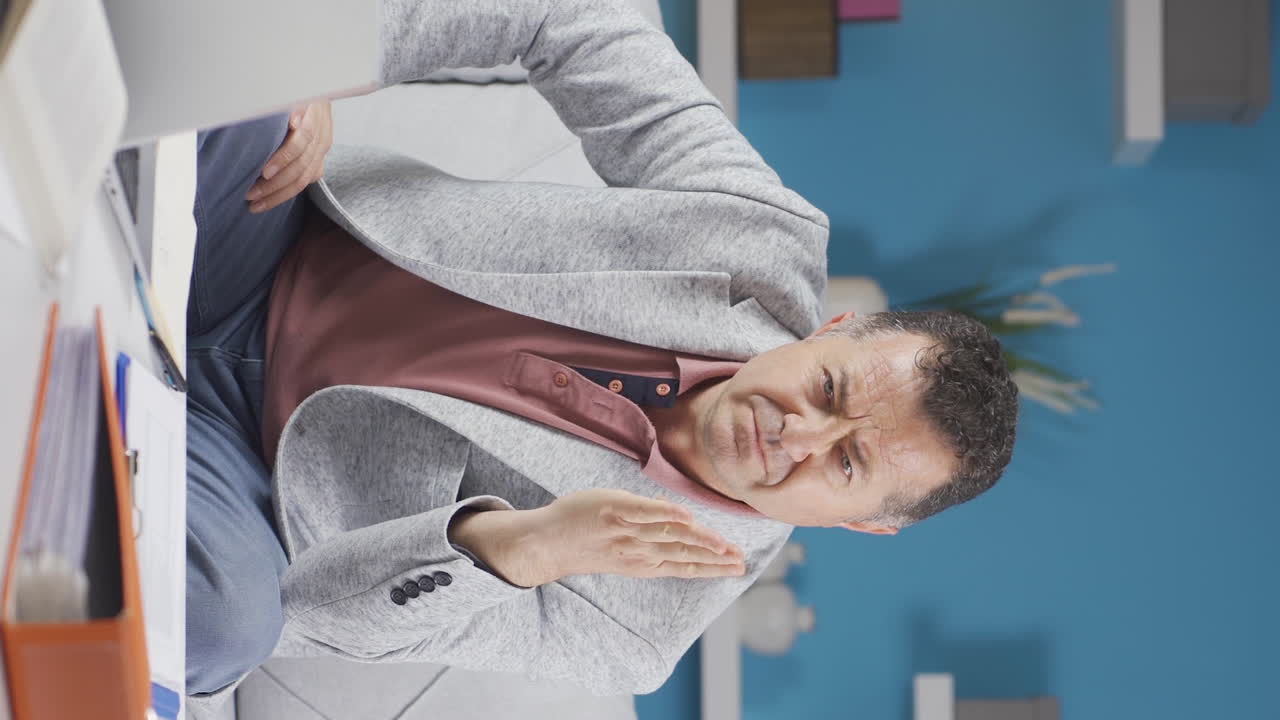 홈 오피스 직원 노인이 카메라를 불안하게 바라보는 수직 비디오.