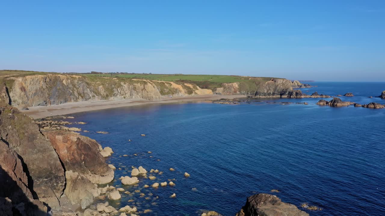 Vista aerea della costa rocciosa e colorata con una spiaggia isolata nel sud dell'Irlanda.