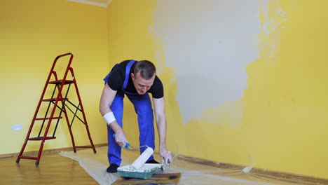 man painting walls with roller. workman in the uniform painting the walls with paint roller