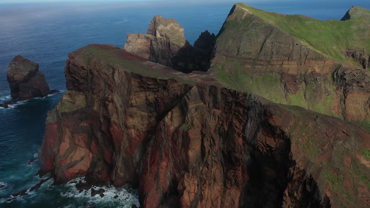 Big, red cliffs with lines and patterns on the edge of the coast in Madeira