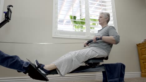 senior woman exercising on a rowing machine - low angle sliding