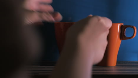 Close-up-clip-of-woman-putting-three-orange-cups-on-the-wood-table-against-blue-background