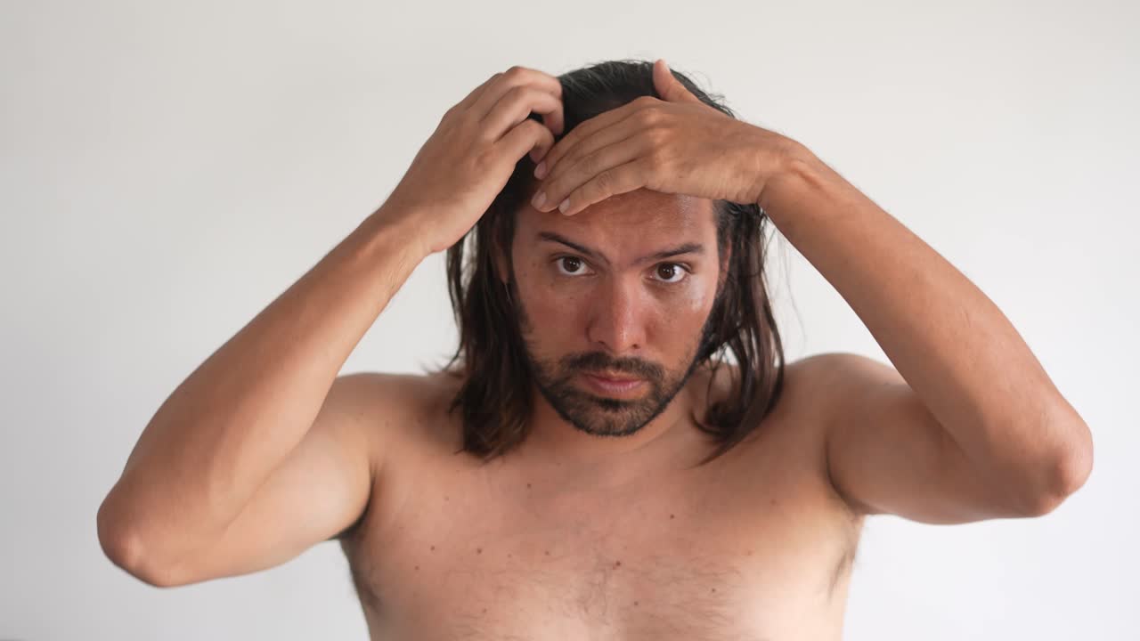 Man with long, wet hair holding his head