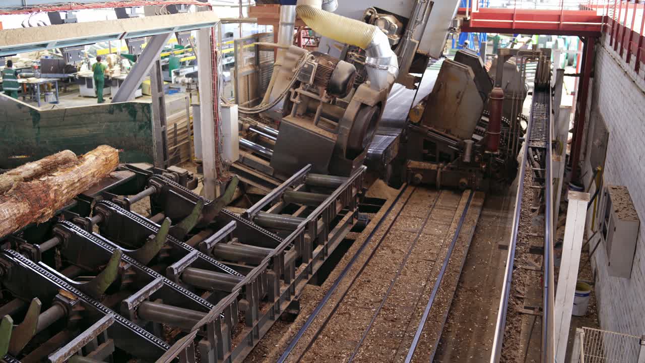 Interior of sawmill with lumber pile. Production of wooden boards with machines