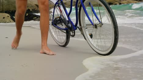 low section of man walking with bicycle on the beach 4k