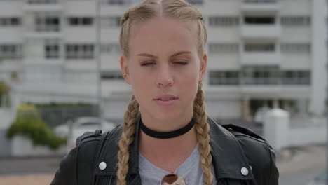 retrato atractiva joven mujer rubia buscando serio independiente mujer caucásica disfrutando de un soleado día urbano en la ciudad con una elegante chaqueta de cuero cámara lenta