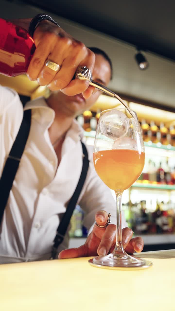 Barman che versa liquido rosso in un bicchiere da cocktail in un bar
