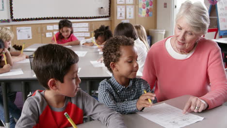 senior teacher helping young schoolboys in class, front view