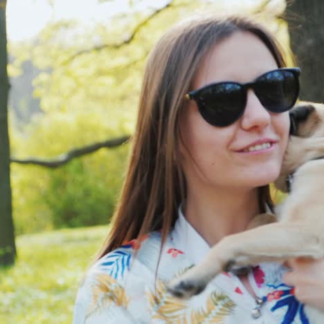 Joven-Mujer-Elegante-Con-Gafas-De-Sol-Caminando-En-El-Parque-Con-Un-Perro-De-Raza-Pug-3