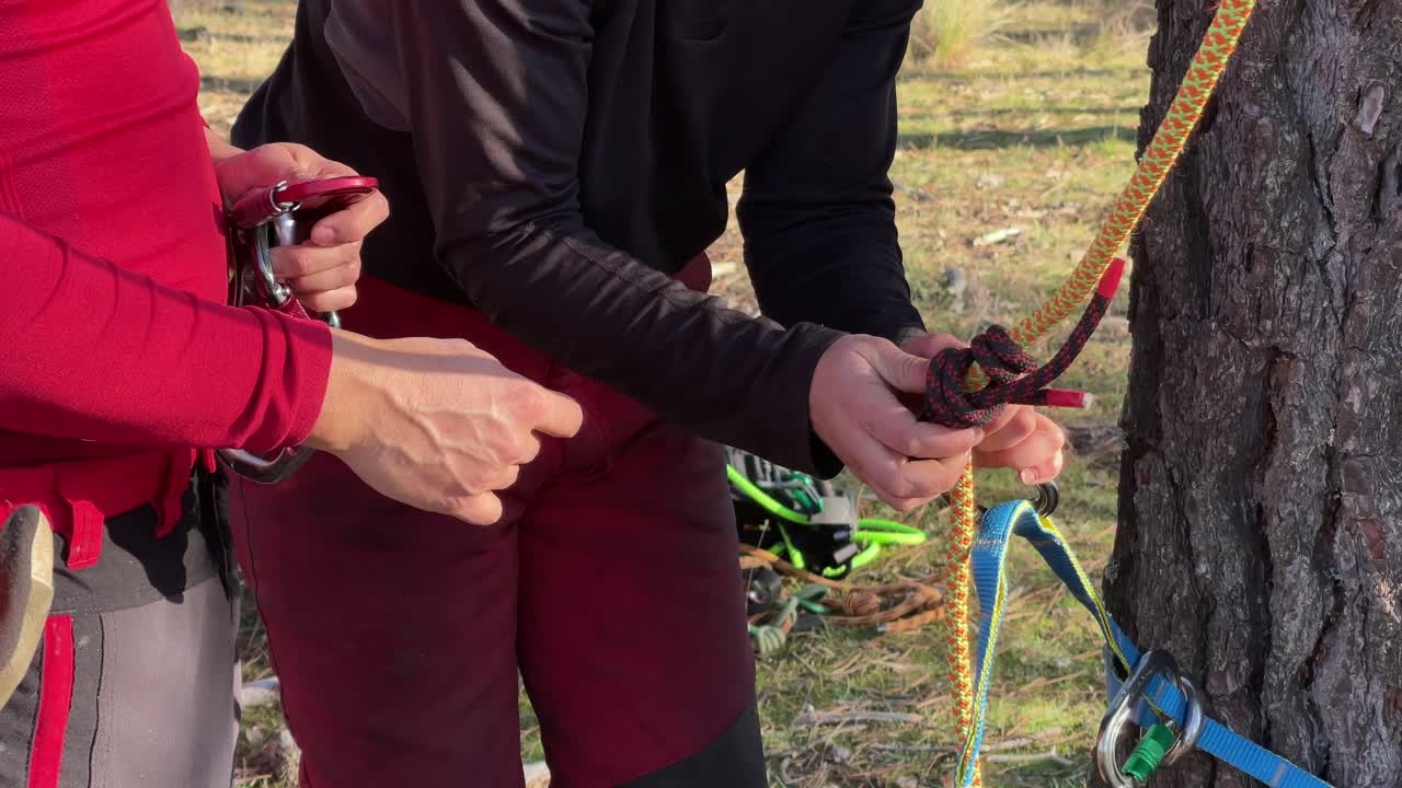 Primo piano delle mani di uomo e donna che annodano in una foresta spagnola, per la potatura in altezza e il giardinaggio.