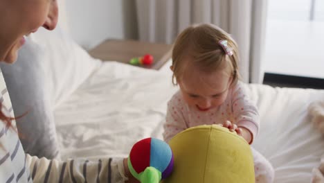 Caucasian-mother-and-baby-playing-with-toys-on-the-bed-at-home