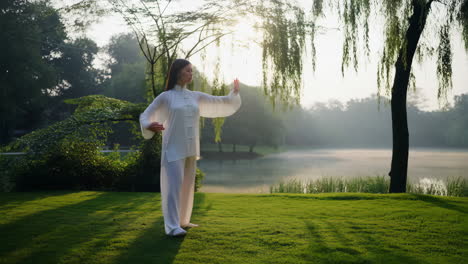 woman practicing tai chi in a peaceful park by the lake at sunrise