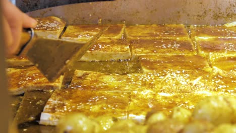 Slow-motion-of-hawker-grilling-and-flipping-over-Sichuan-traditional-street-food-Tofu-on-iron-plate,-at-famous-Kuanzhai-Alley,China-Chengu-attraction