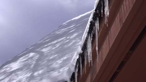 Icicles-drip-water-from-a-rooftop-during-a-winter-storm