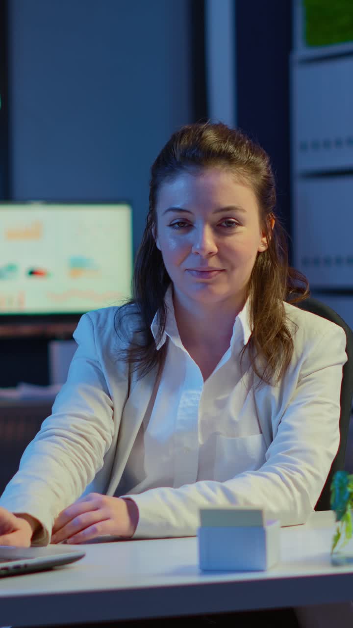 Vertical video: Business woman looking at camera smiling after typing on laptop