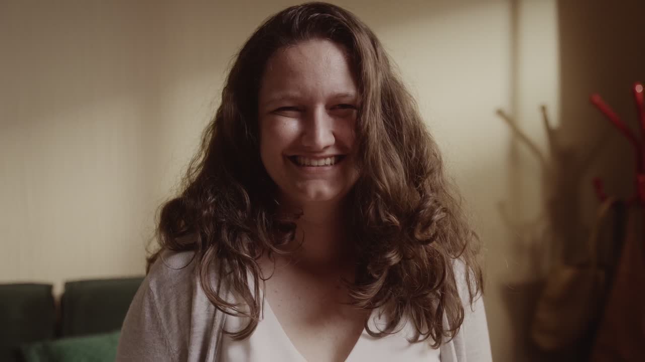 A smiling woman with long brown hair indoors