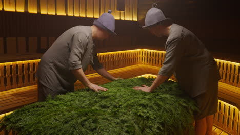 men preparing a sauna with fir branches