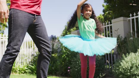 Happy-biracial-father-and-daughter-dancing-in-garden-together